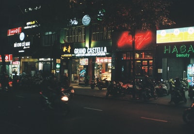 人们在夜间走在商店附近的人行道上